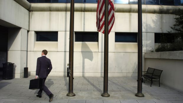 A businessman walks past a U.S. flag flying at half mast as people return to work at the Fulton County Superior Courthouse on March 14th, 2005, in Atlanta, Georgia.