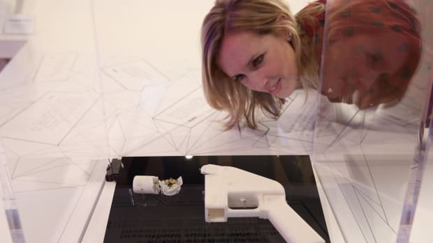 A woman admires a 3-D printed handgun on display in a museum.