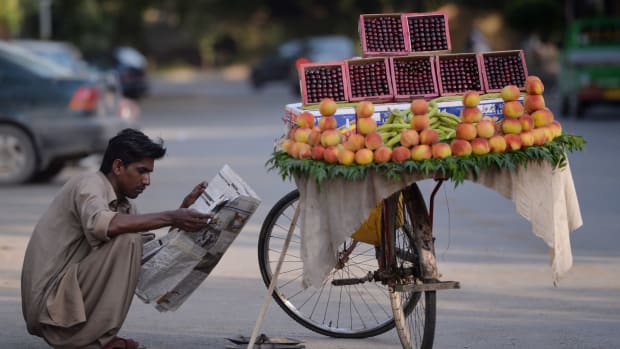 A fruit vendor reads a newspaper as he waits for customers on a street in Islamabad, Pakistan, on May 23rd, 2017.