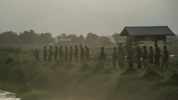 The Myanmar Police Force stand guard by a slum near the outskirts of Yangon on June 12th, 2017.