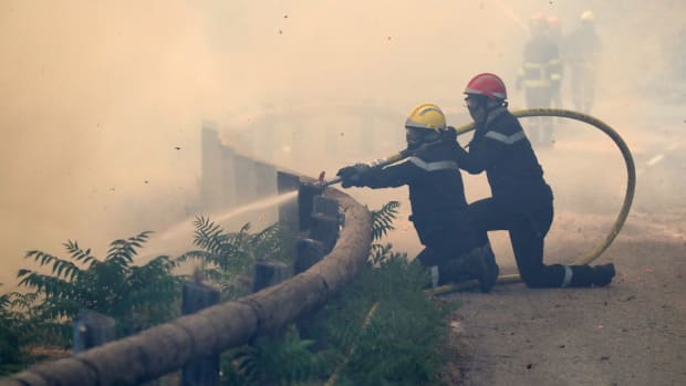 Firefighters use a hose to spray water as they fight against a fire in Castagniers, France, on July 17th, 2017.