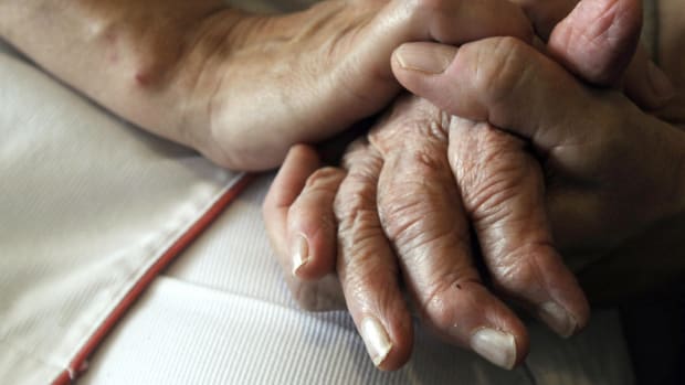 A nurse holds the hands of a person suffering from Alzheimer's disease.