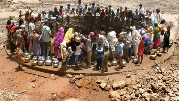 Indian villagers gather around a well to fill their pots with water at Natwargadh village.