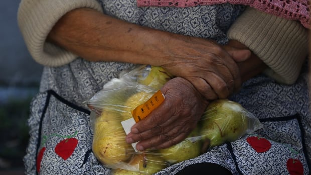 A woman holds a bag of pears as she waits in line to receive free food at the Richmond Emergency Food Bank on November 1st, 2013, in Richmond, California.