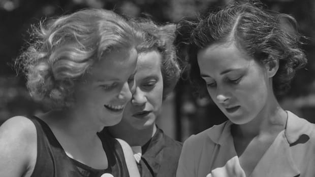 Three female students reading a book circa 1950.