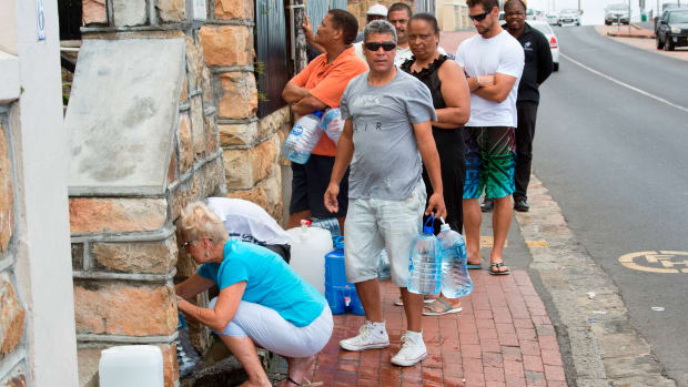 People collect drinking water from pipes fed by an underground spring, in St. James, about 25km from Cape Town's city center, on January 19th, 2018.