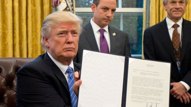 President Donald Trump shows the executive order withdrawing the U.S. from the Trans-Pacific Partnership after signing it in the Oval Office of the White House.