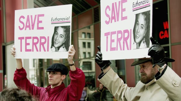 John Jansen and Joseph Scheidler carry signs calling for continued care and feeding of Terry Schiavo during a protest at the Thompson Center Plaza on March 29th, 2005, in Chicago, Illinois.