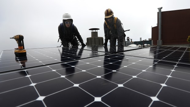 Workers install solar panels on the roof of a home on May 9th, 2018, in San Francisco, California.