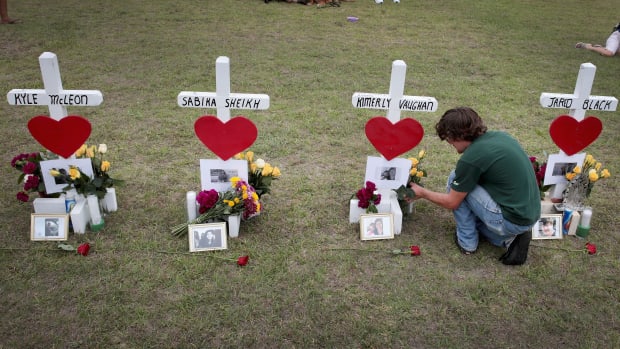 James Otto, a 2011 graduate of Santa Fe High School, leaves flowers at a memorial in front of the school on May 21st, 2018, in Santa Fe, Texas.
