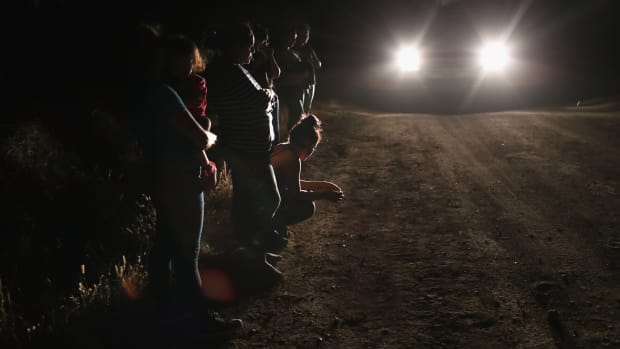 Central American asylum seekers wait for transport while being detained by U.S. Border Patrol agents near the U.S.-Mexico border on June 12th, 2018, in McAllen, Texas. The group of women and children had rafted across the Rio Grande from Mexico and were detained before being sent to a processing center for possible separation.