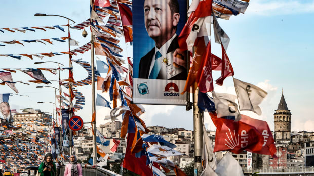 Women walk on a bridge past campaign banners with the portrait of Turkey's president in Istanbul on June 18th, 2018. Turkey prepares for tight presidential and parliamentary elections on June 24th, while many analysts say President Recep Tayyip Erdogan wants a major foreign policy success to give him a final boost. The slogan reads "A big Turkey wishes a powerful leader."