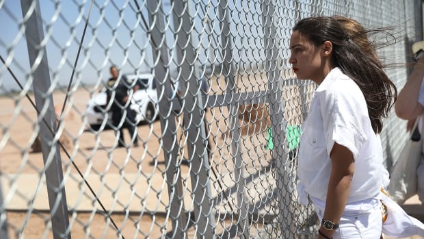 Alexandria Ocasio-Cortez stands at the Tornillo-Guadalupe port of entry gate on June 24th, 2018, in Tornillo, Texas.