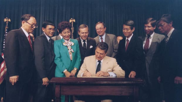 President Ronald Reagan signs the Civil Liberties Act of 1988 on August 10th, 1988, which granted reparations for the internment of Japanese Americans.