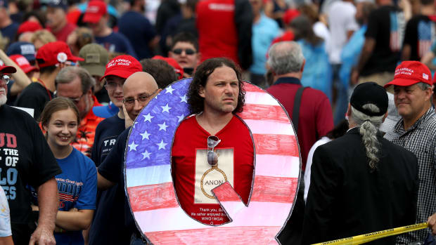 A man holds a large Q sign, referencing the Qanon conspiracy theory, at a rally for President Donald Trump on August 2nd, 2018, in Wilkes Barre, Pennsylvania.