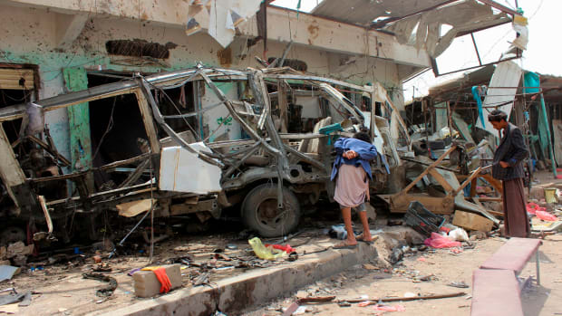 Yemenis gather next to the destroyed bus at the site of a Saudi-led coalition airstrike, on August 10th, 2018.