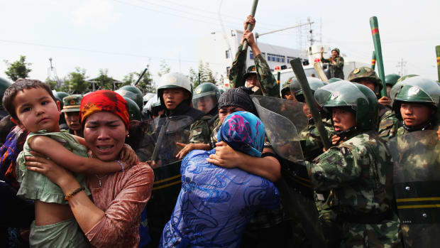 Chinese policemen push Uighur women who are protesting at a street on July 7th, 2009, in Urumqi, China.