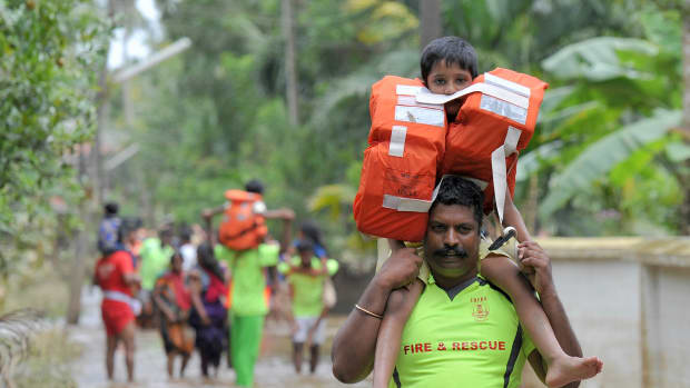 Rescue personnel carry children on their shoulders through flood waters during a rescue operation in Annamanada, a village in India, on August 19th, 2018. Rescuers waded into submerged villages in a desperate search for survivors cut off for days by floods that have already killed more than 350 people.