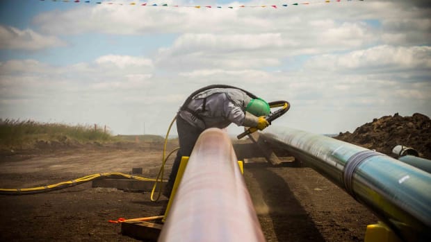 A construction worker specializing in pipe-laying sandblasts a section of pipeline on July 25th, 2013, outside Watford City, North Dakota.