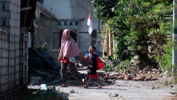 Residents walk among debris in the village of Sugian on Indonesia's Lombok Island on August 21st, 2018, after a series of recent earthquakes. Indonesian aid agencies and government officials rushed to help survivors after another series of powerful quakes rattled the island, killing at least 14 people and leaving hundreds of thousands homeless.