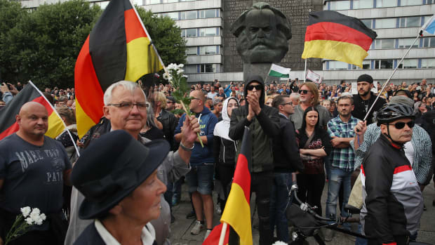 People holding German flags arrive at a right-wing protest gathering near a statue of Karl Marx the day after a man was stabbed and died of his injuries on August 27th, 2018, in Chemnitz, Germany. A German man died after being stabbed in the early hours of August 26th following an altercation, leading a xenophobic mob of approximately 800 people to take to the streets. Left- and right-wing groups of over a thousand people each confronted each other as riot police stood in between.