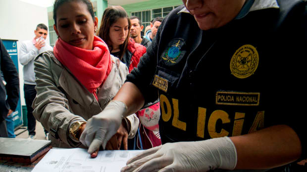 A policeman takes fingerprints of a Venezuelan migrant as a group of migrants wait to apply for resident visas or temporary stay permits at an Interpol facility in Lima, Peru, on August 29th, 2018. Last Friday, Peru enacted rules that mandated that Venezuelans coming into the country show a passport (previously, the law only required an identification card). Since then, hundreds of Venezuelans have applied for asylum in Peru. As Venezuela suffers an unprecedented economic and humanitarian crisis, hundreds of thousands of Venezuelans have fled into other South American countries, escaping intolerable food and medicine shortages in their home country.