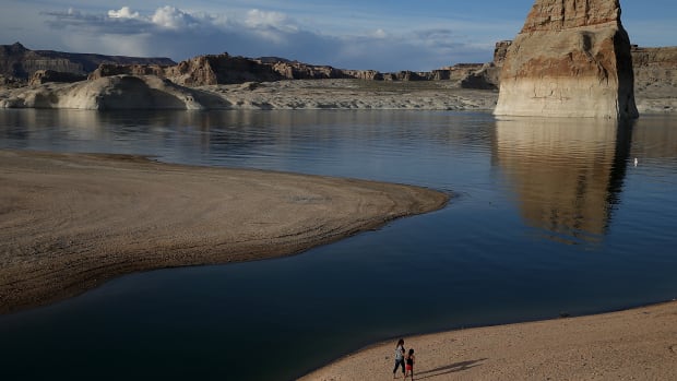 People walk on a beach that used to be the bottom of Lake Powell on March 29th, 2015, near Big Water, Utah. Lake Powell is one of the Colorado River Basin's two biggest reservoirs, along with Lake Mead.