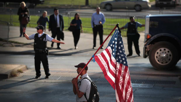A demonstrator holds an American flag emblazoned with the names of victims who were fatally wounded by police officers during a protest outside the Leighton Criminal Courthouse Building on the first day of Chicago police officer Jason Van Dyke's murder trial on Monday, September 17th, 2018, in Chicago, Illinois. Van Dyke faces murder charges for shooting 17-year-old Laquan McDonald 16 times in an October of 2014 confrontation.
