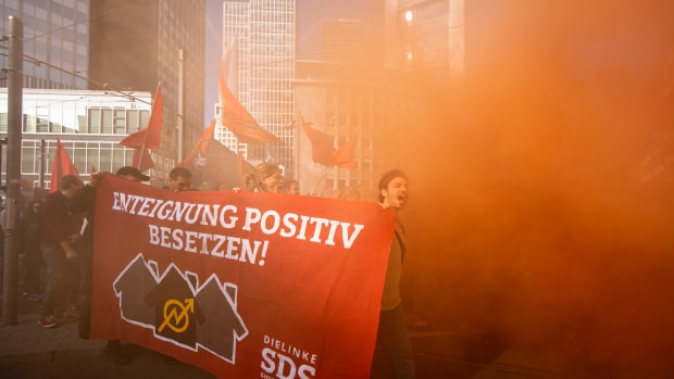 Protesters walk in the smoke while demonstrating against rising housing rental prices on October 20th, 2018, in Frankfurt, Germany. Skyrocketing costs for housing have become a major issue in cities across Germany, with local government scrambling to find policy solutions. Frankfurt in particular is already attracting wealthy newcomers as the city becomes an alternative for companies in the financial sphere relocating from Brexit-afflicted London. In other cities, especially Berlin, foreign investors, including from China, are parking their money in luxury apartment purchases.