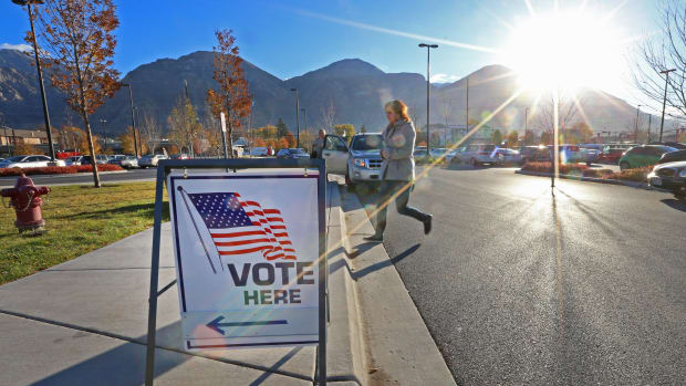 A woman walks into a polling center to vote in the mid-term elections as the morning sun rises over the Utah Wasatch Mountains on November 6th, 2018, in Provo, Utah.