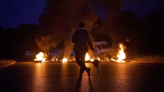 A protester watches a burning traffic circle while union trade members block trucks on September 25th, 2017, in Donges, France, to protest the government's labor law.