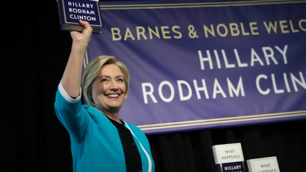 Former U.S. Secretary of State Hillary Clinton holds up a copy of her new book What Happened at a book signing event at a Barnes and Noble bookstore on September 12th, 2017, in New York City.