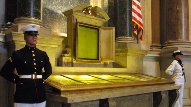 An honor guard stands next to the original copies of the Declaration of Independence, the Constitution, and the Bill of Rights on July 4th, 2001, at the National Archives in Washington, D.C.