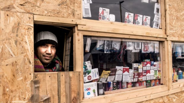 A Pakistani migrant looks out of his shop set-up at "the Jungle" in the French port city of Calais.