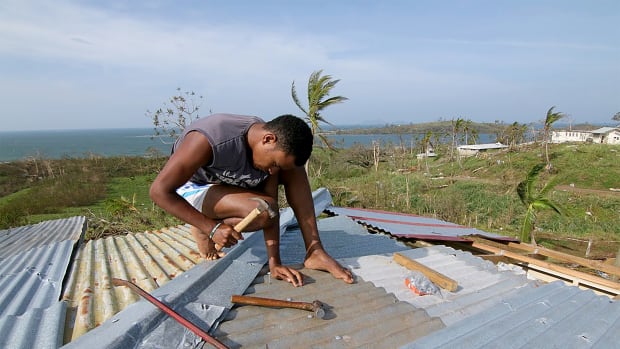 A young man repairs the roof of his house in Tailevu after Cyclone Winston swept through Fiji in 2016.