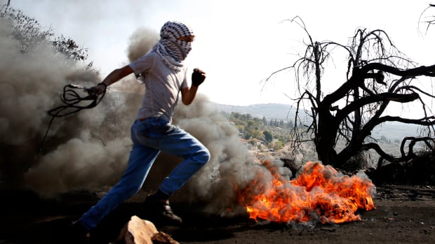 A Palestinian protester runs past burning tires during a clash with Israeli forces over occupation in the village of Kfar Qaddum, near the occupied West Bank, on November 10th, 2017.