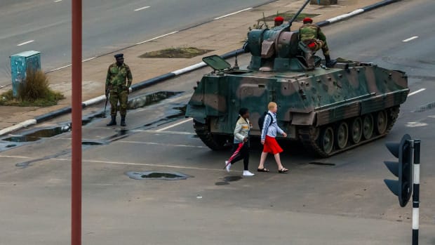 Pedestrians pass a tank stationed at an intersection as Zimbabwean soldiers regulate traffic in Harare on November 15th, 2017. Zimbabwe's military placed President Robert Mugabe under house arrest and took control of the country in an apparent coup on Wednesday.