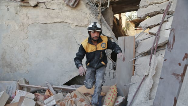 A volunteer from the Syrian Civil Defence searches the rubble of a building following a reported airstrike in the rebel-controlled town of Hamouria on the outskirts of Damascus on November 28th, 2017.