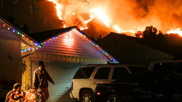 A man prepares to evacuate his home as a wildfire burns along a hillside near homes in Santa Paula, California.