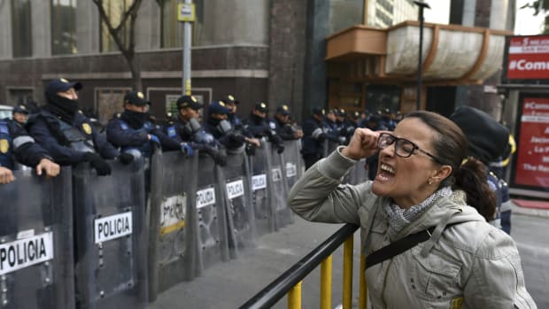 A demonstrator shouts slogans in front of the Senate building during a protest against the potential approval of an internal security law that would allow the army to act as police, in Mexico City, on December 14th, 2017. Mexican deputies approved a new security law that provides a legal framework for military deployment. The controversial initiative is being discussed in the Senate.