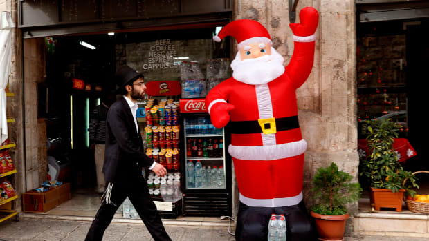 An orthodox Jewish Israeli walks past an inflatable figure of Santa Claus in the Christian Quarter of Jerusalem on December 20th, 2017.