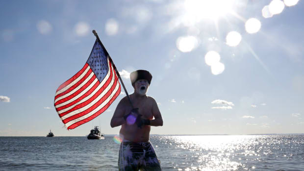 A Polar Bear Club swimmer carries an American flag as the group makes its annual icy plunge into the Atlantic Ocean on January 1st, 2018, on Coney Island in the Brooklyn borough of New York City.