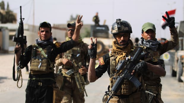 Iraqi forces are seen flashing the sign for victory on November 4th, 2017, in the center of the city of al-Qaim.