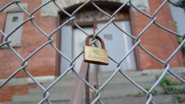 A padlock hangs outside a shuttered schoolhouse in New York.