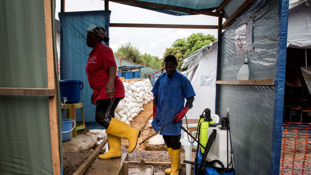 A worker at an emergency cholera treatment center gets her shoes disinfected in Kinshasa, the Democratic Republic of the Congo, on January 18th, 2018. The World Health Organization said this week that there was a high risk of a cholera epidemic after flooding in the area.