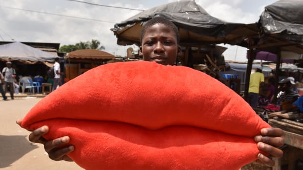 A boy poses with a pillow shaped like lips on sale for Valentine's Day in Yopougon, Ivory Coast, on February 13th, 2018.