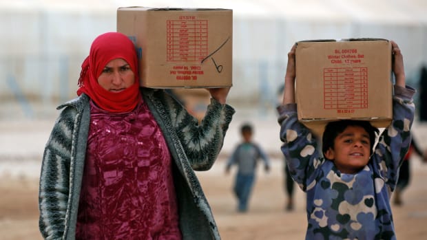 Displaced Syrians, who fled their homes in the eastern Syrian city of Deir Ezzor, carry boxes of humanitarian aid supplied by the United Nations Children's Fund at a refugee camp in Syria's northeastern Hassakeh province on February 26th, 2018.