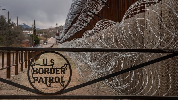 A metal fence marked with the U.S. Border Patrol sign prevents people from getting close to the barbed/concertina wire covering the U.S.–Mexico border fence, in Nogales, Arizona, on February 9th, 2019.