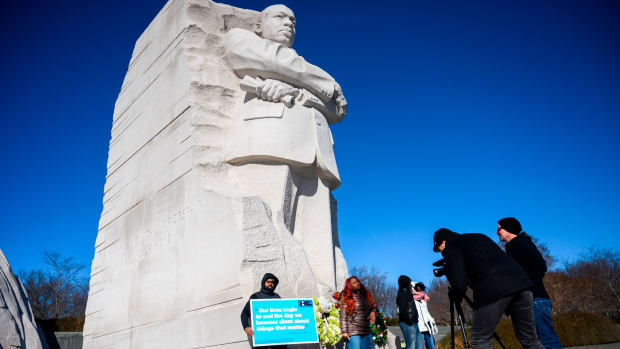 People visit the Martin Luther King Jr. Memorial in Washington, D.C., for Martin Luther King Day on January 21st, 2019. The man holds a sign that quotes Martin Luther King Jr. It reads, "Our lives begin to end the day we become silent about things that matter."