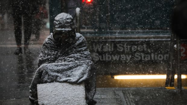 A homeless man sits in the falling snow in the Financial District on January 30th, 2019, in New York City.